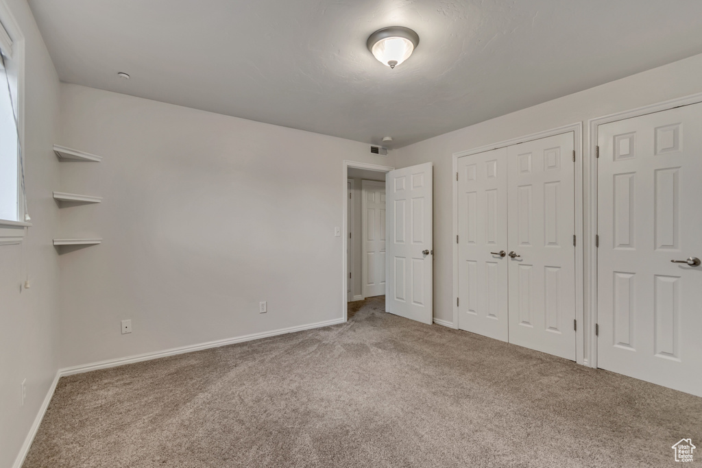 Unfurnished bedroom featuring carpet floors, baseboards, and multiple closets