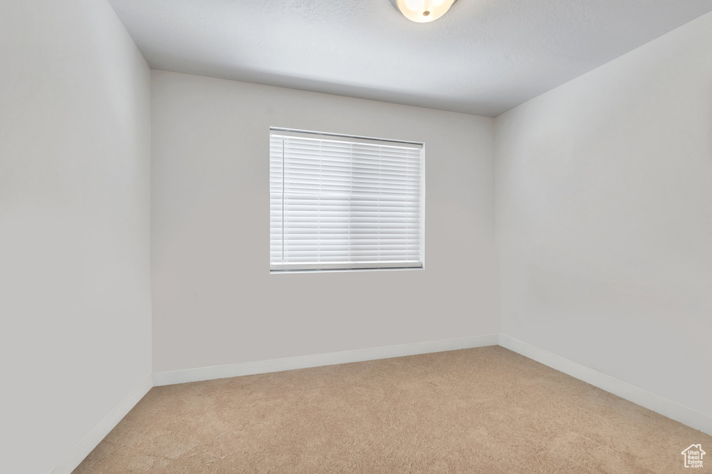 Carpeted empty room featuring baseboards