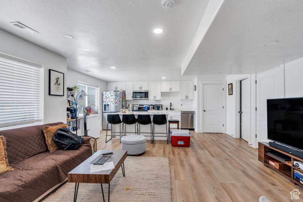 Living room featuring light wood-style flooring, recessed lighting, and a textured ceiling