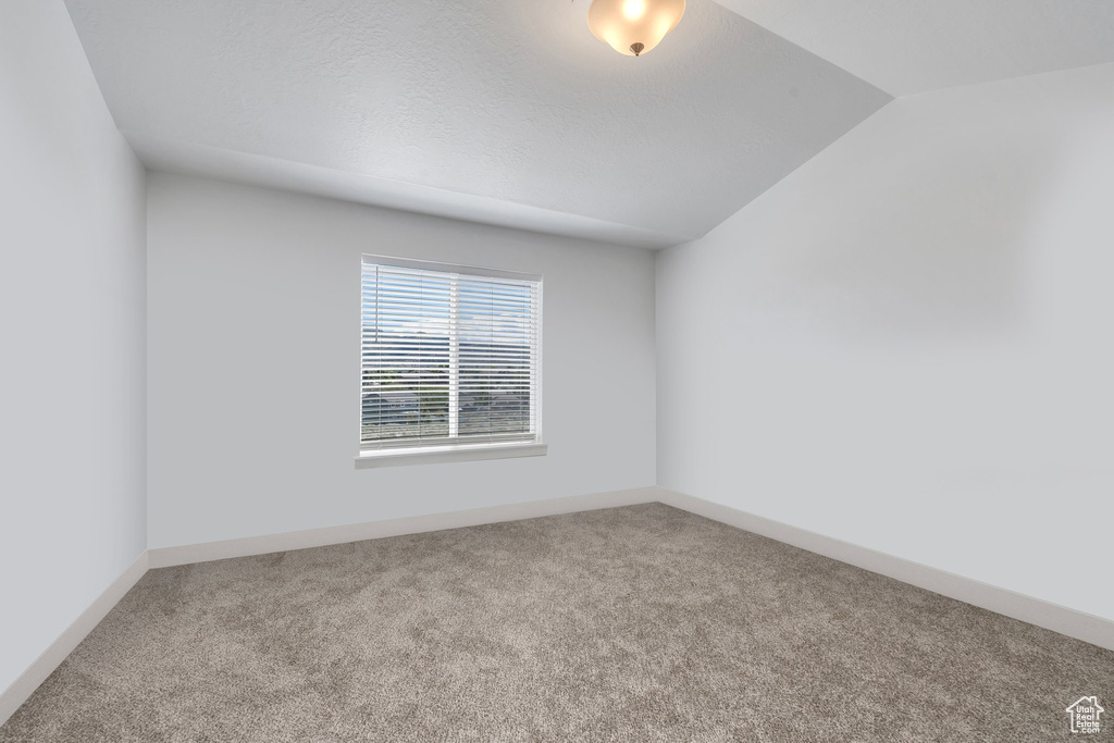 Empty room with carpet, lofted ceiling, and baseboards