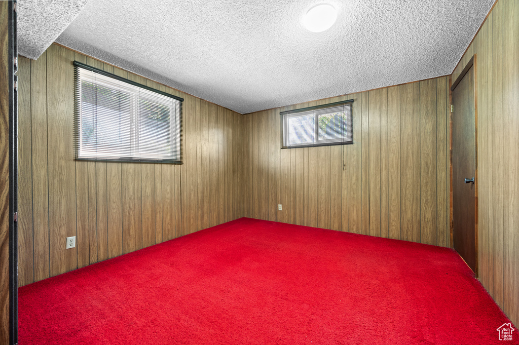Carpeted spare room featuring a textured ceiling and wood walls