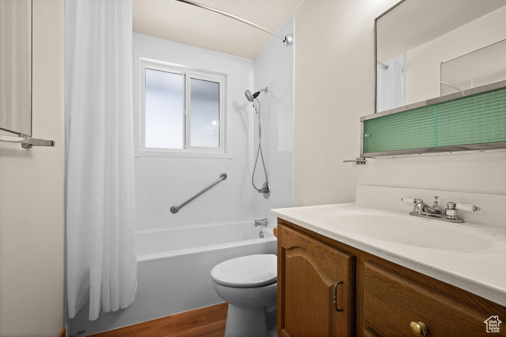 Full bath with vanity, shower / tub combo, toilet, and wood finished floors