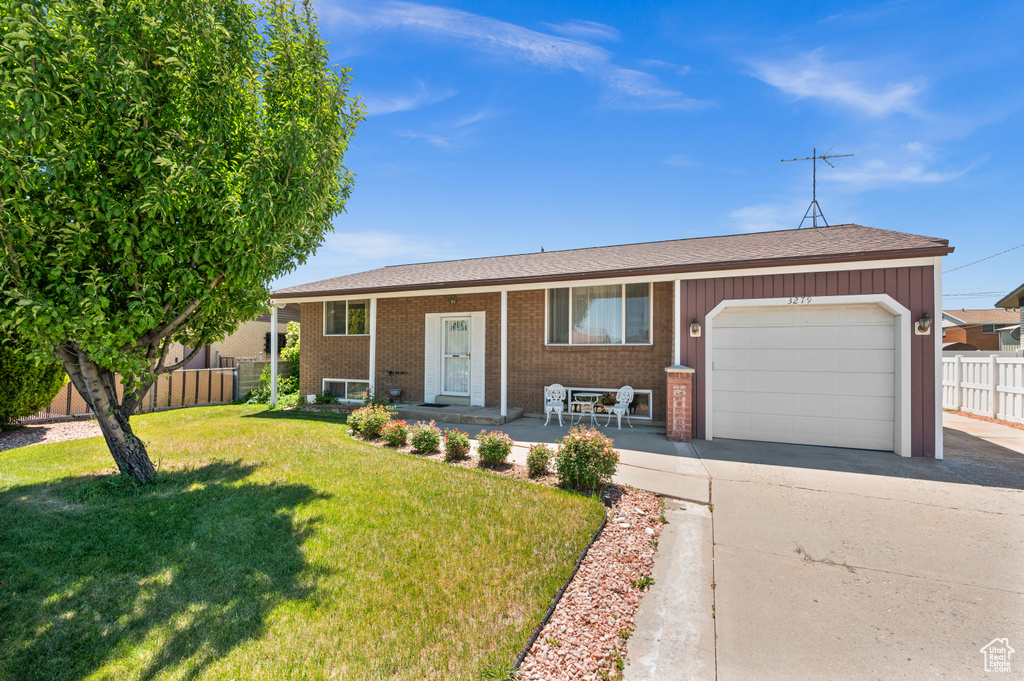 Raised ranch featuring an attached garage, concrete driveway, covered porch, and brick siding