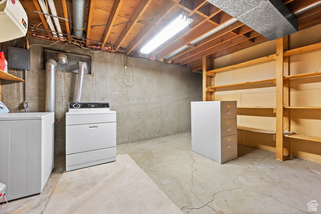 Unfinished basement featuring separate washer and dryer and electric panel