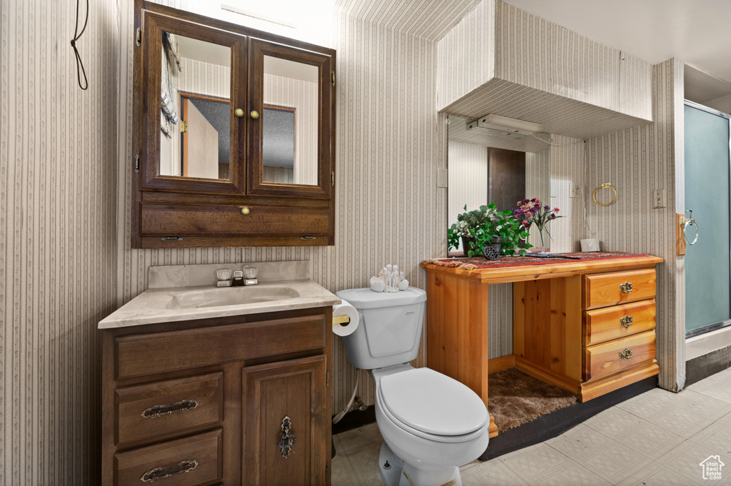 Full bathroom with wallpapered walls, vanity, a shower stall, toilet, and tile patterned floors