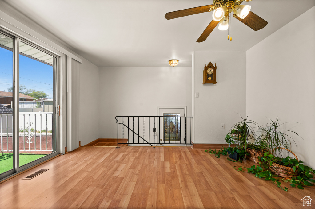 Unfurnished room with light wood-style floors, baseboards, and a ceiling fan