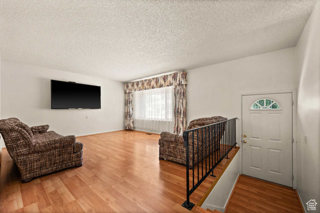 Living room with plenty of natural light, a textured ceiling, wood finished floors, and baseboards