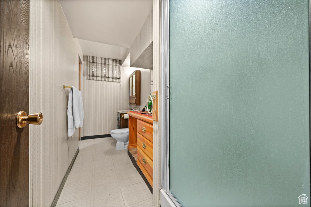 Full bathroom with vanity, toilet, baseboards, a shower with door, and tile patterned floors