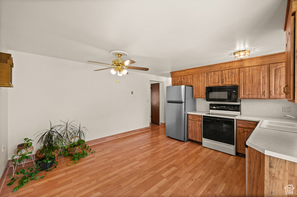 Kitchen featuring white range with electric cooktop, freestanding refrigerator, black microwave, a sink, and light countertops