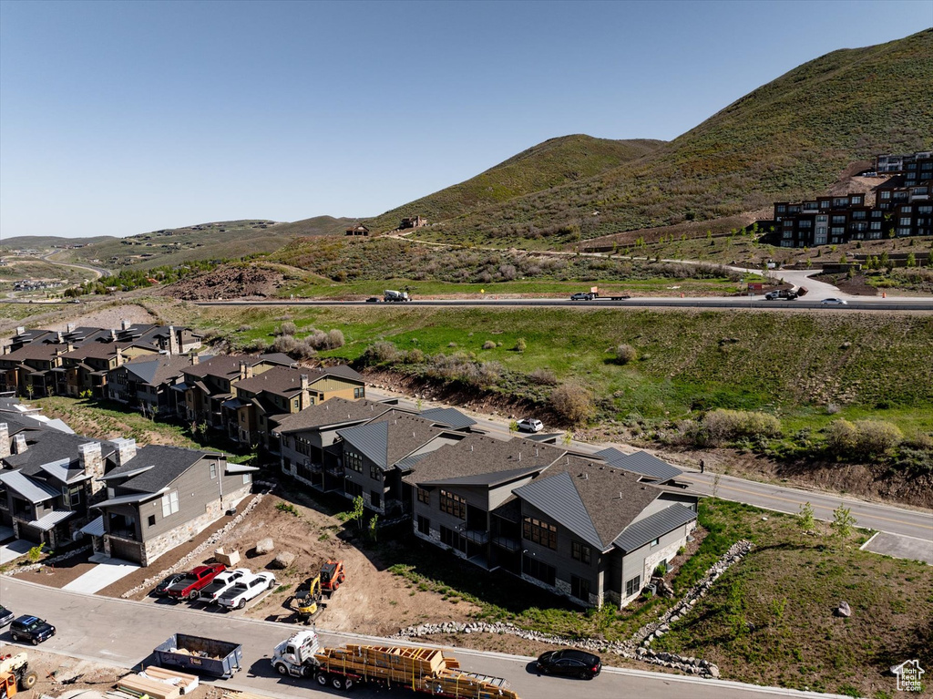 Aerial view of property and surrounding area featuring mountains and nearby suburban area