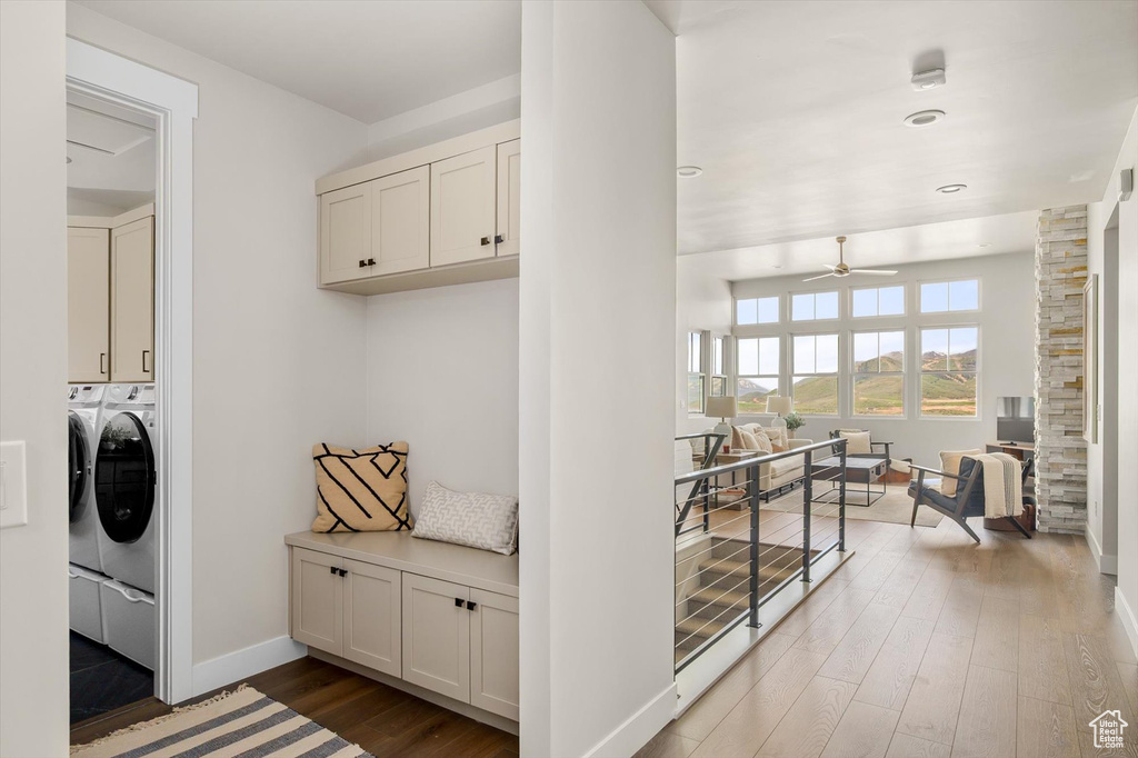 Laundry area with independent washer and dryer, cabinet space, ceiling fan, wood finished floors, and baseboards