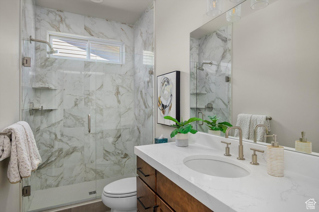 Bathroom featuring vanity, toilet, and a marble finish shower