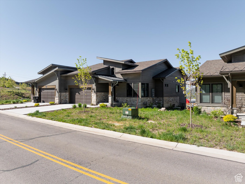 View of front facade featuring stone siding, an attached garage, and concrete driveway