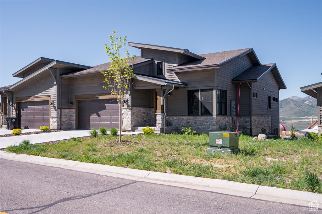 View of front of house featuring a garage, stone siding, concrete driveway, and a mountain view