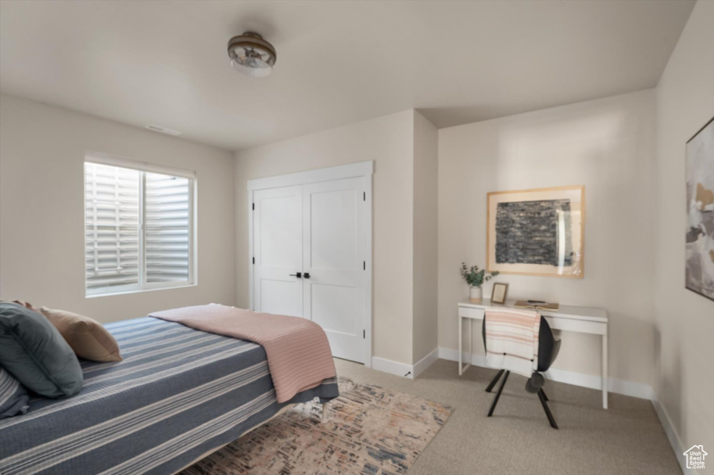 Carpeted bedroom with baseboards, an office area, and a closet