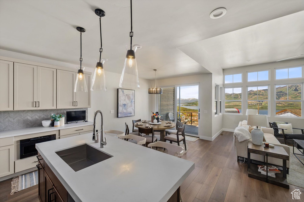 Kitchen with a sink, light countertops, tasteful backsplash, dark wood-style floors, and hanging light fixtures