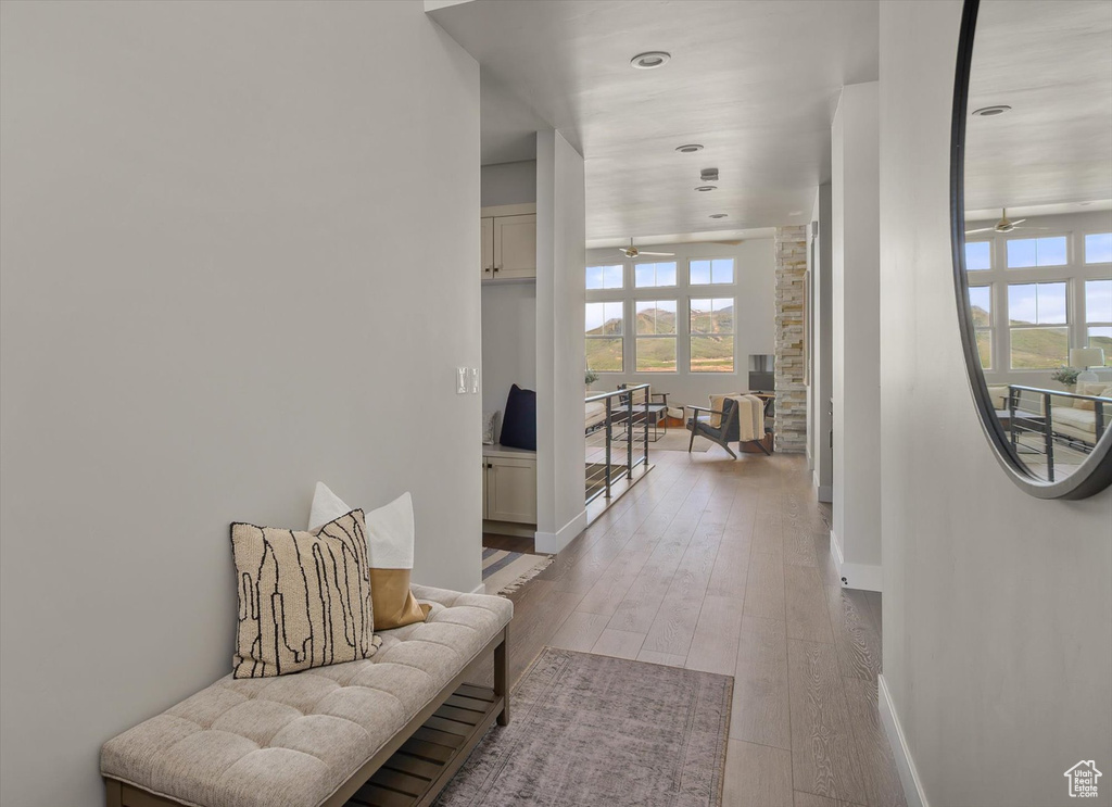 Corridor with healthy amount of natural light, baseboards, light wood-style flooring, and recessed lighting