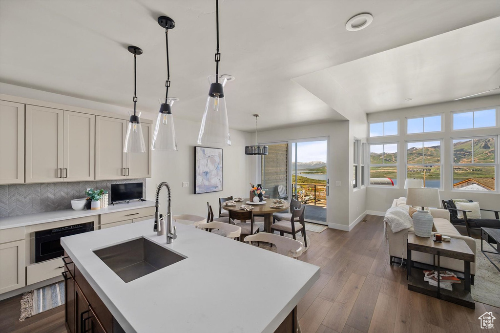 Kitchen featuring a sink, light countertops, backsplash, dark wood finished floors, and baseboards