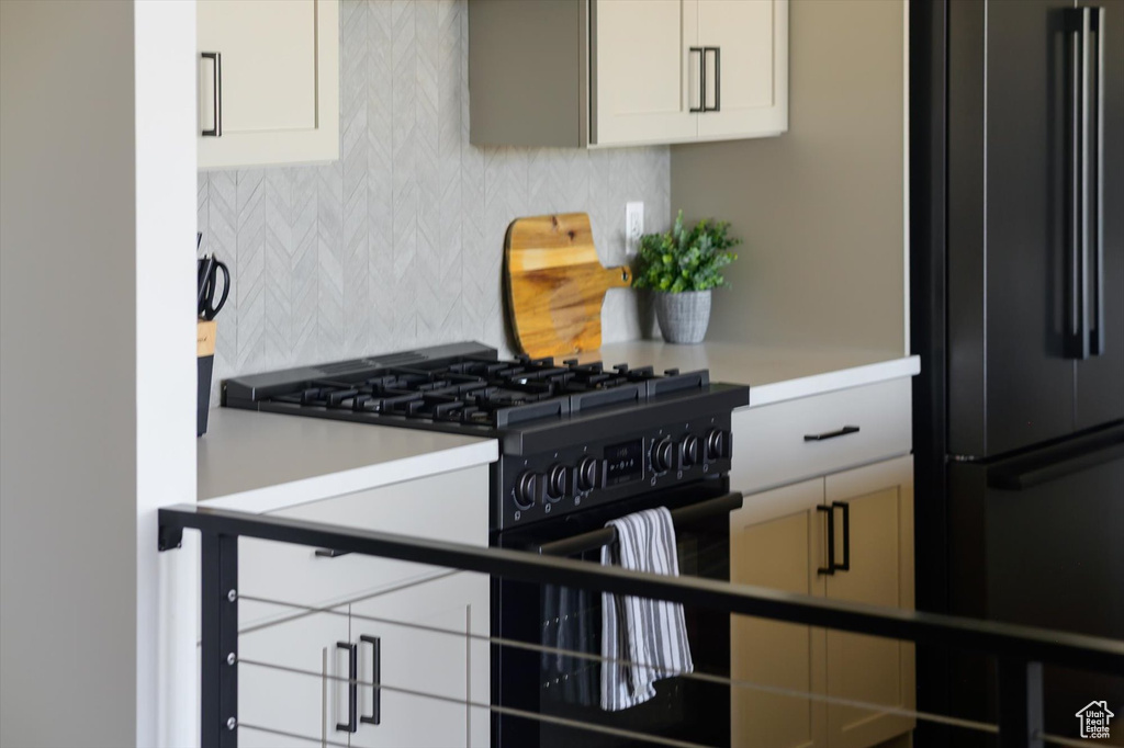 Kitchen featuring black appliances, decorative backsplash, and light countertops