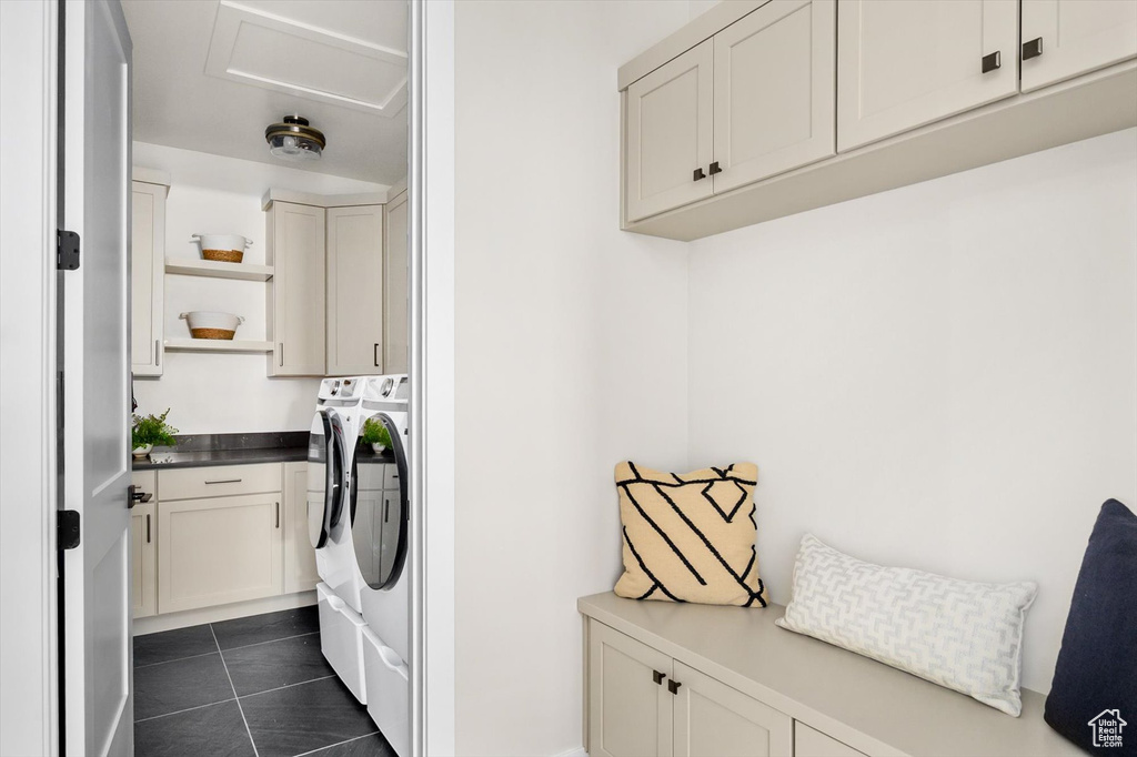 Laundry room featuring cabinet space, washer and clothes dryer, and dark tile patterned flooring