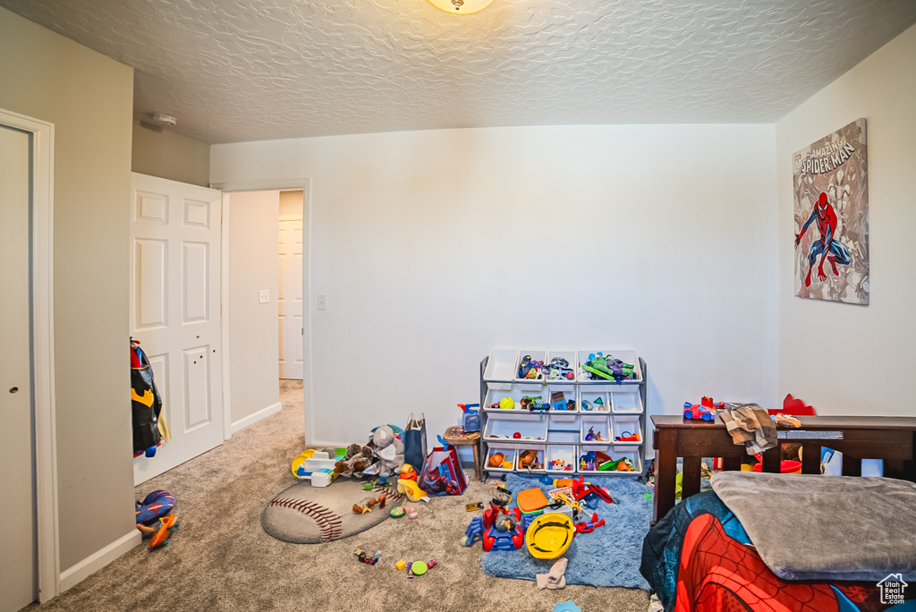 Bedroom with carpet, a textured ceiling, and baseboards