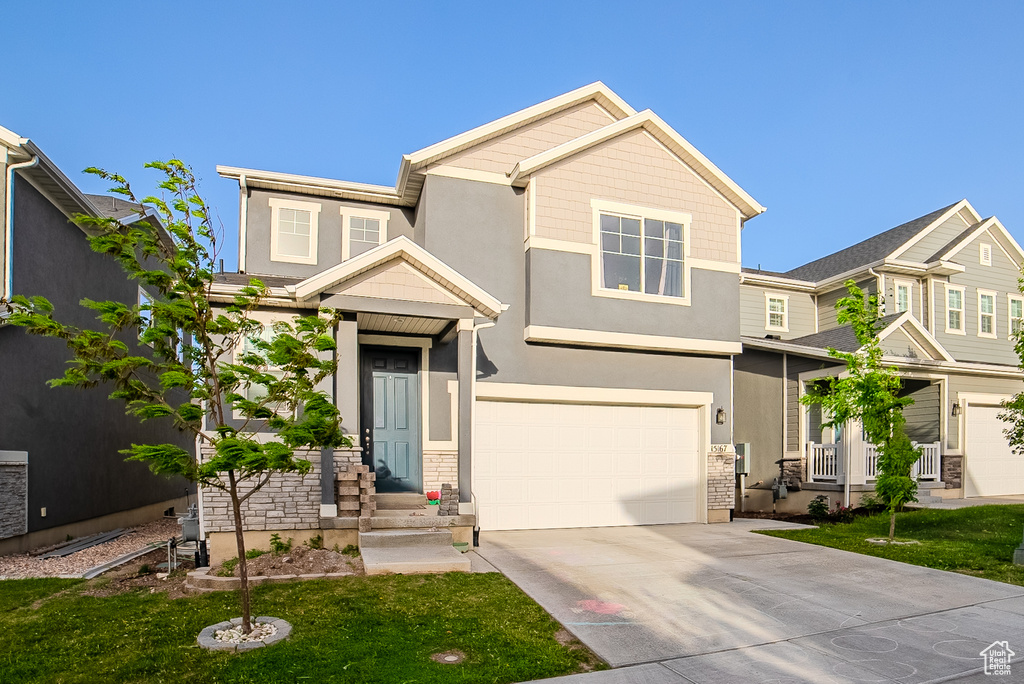 View of front of property with driveway, stucco siding, a garage, and a front lawn