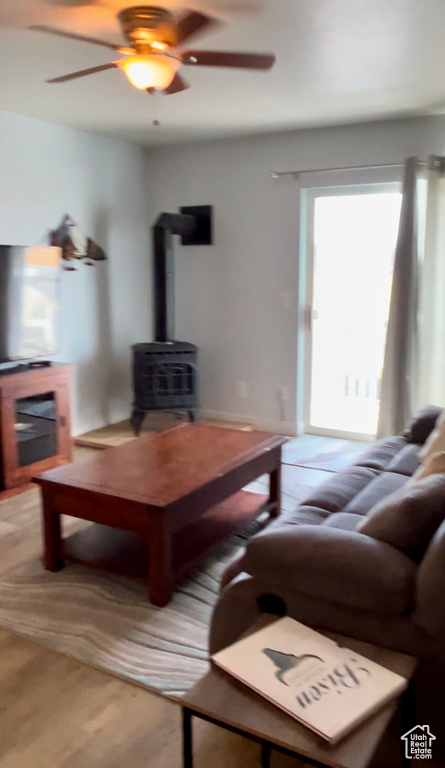 Living room featuring a wood stove, a ceiling fan, and light carpet