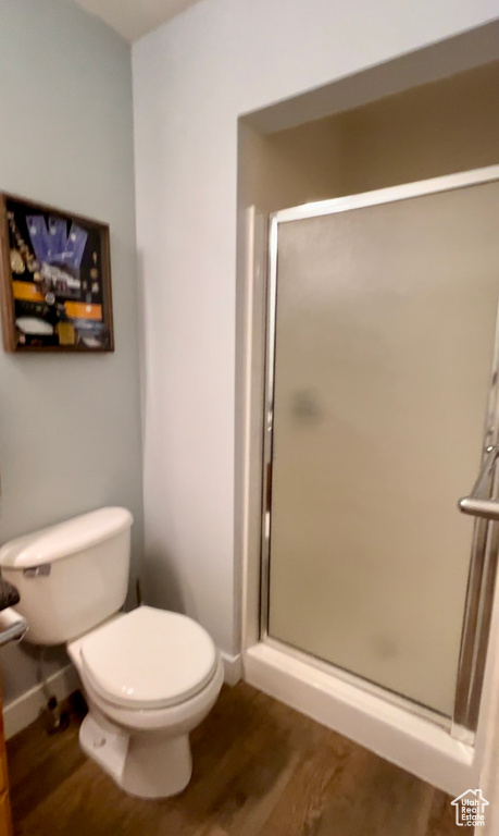 Bathroom featuring toilet, wood finished floors, a shower stall, and baseboards