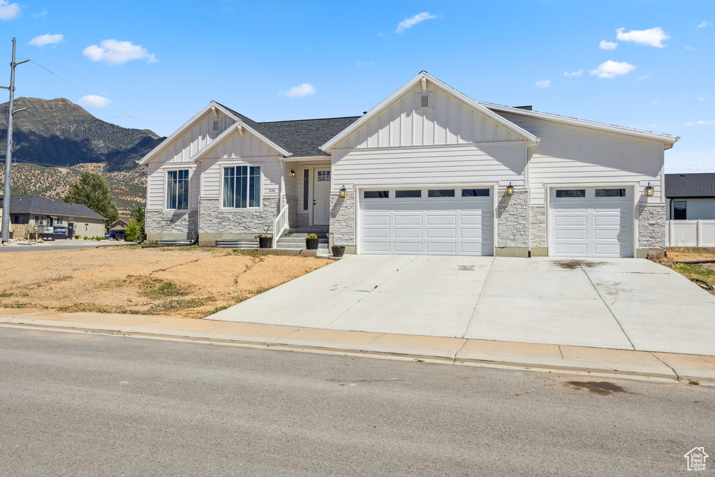 View of front of house with board and batten siding, stone siding, a mountain view, and an attached garage