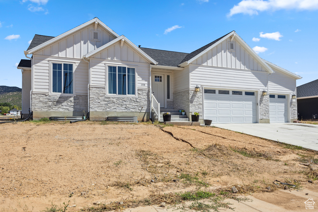 View of front of home with board and batten siding, stone siding, and an attached garage