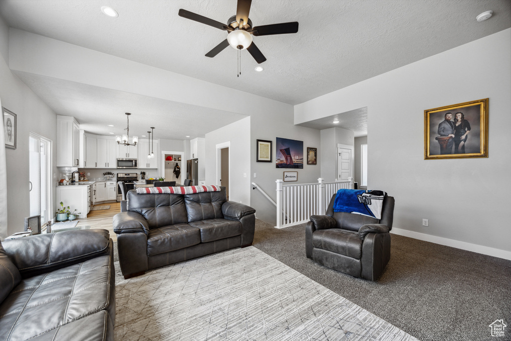 Living room featuring a chandelier, a ceiling fan, recessed lighting, baseboards, and light carpet
