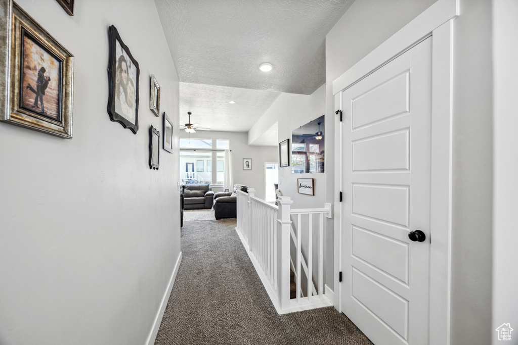 Corridor with carpet, an upstairs landing, a textured ceiling, baseboards, and recessed lighting