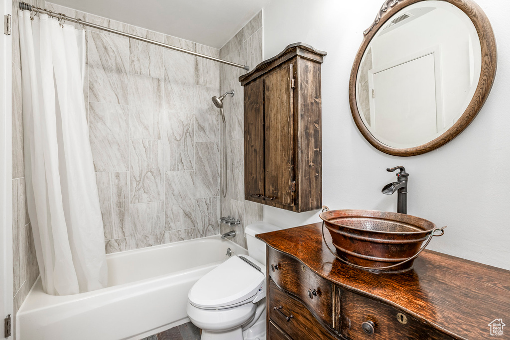 Bathroom with shower / bath combo with shower curtain, vanity, and toilet