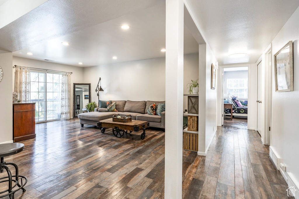 Living room with dark wood-style floors, plenty of natural light, recessed lighting, and baseboards