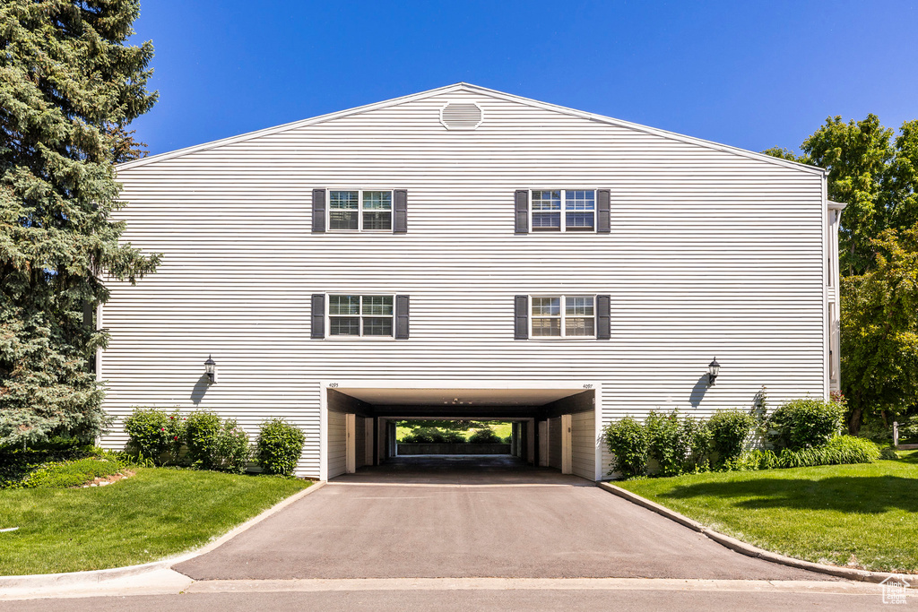 View of property exterior featuring a carport, asphalt driveway, and a yard