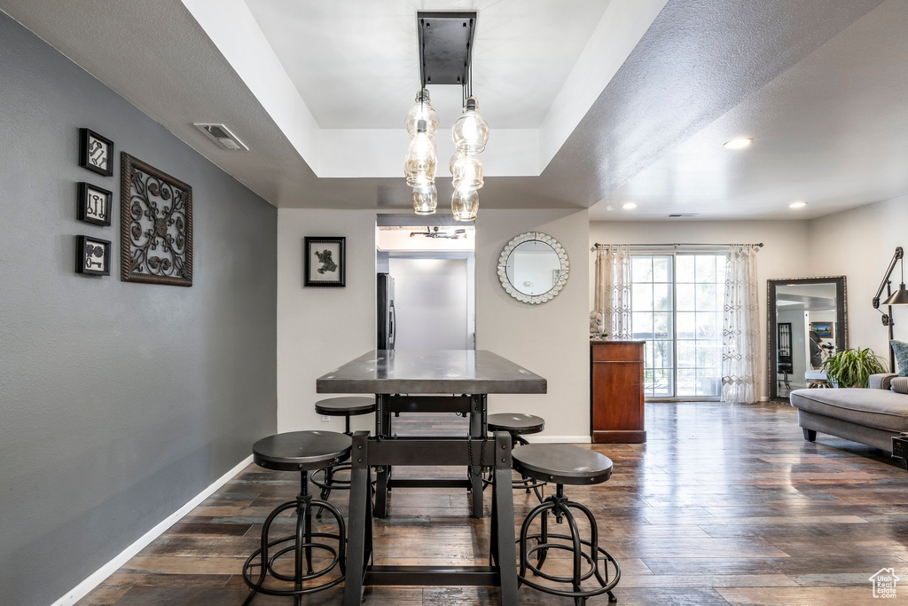 Dining room featuring baseboards, dark wood-style floors, a tray ceiling, and recessed lighting