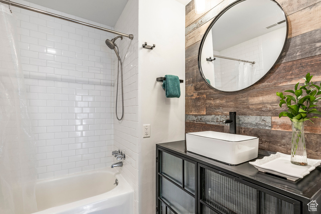 Bathroom with shower / bath combo, vanity, and wooden walls