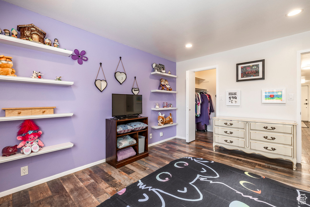 Bedroom with wood finished floors, a walk in closet, baseboards, a closet, and recessed lighting