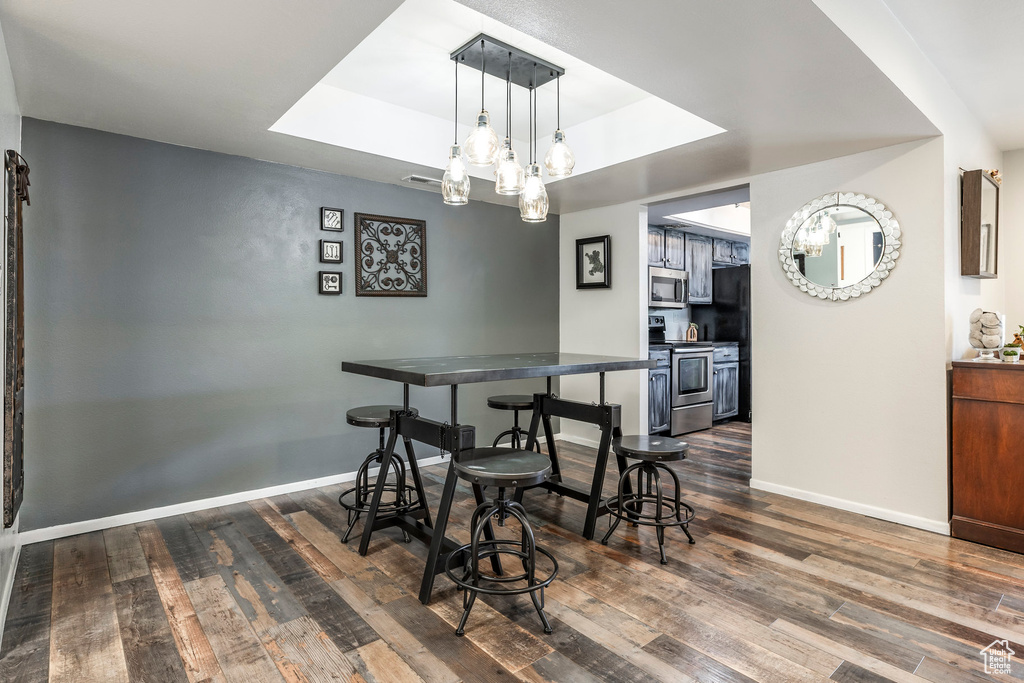 Dining area featuring dark wood-type flooring, a tray ceiling, and baseboards
