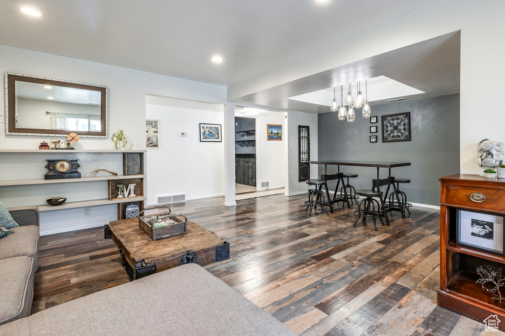 Living room with wood finished floors, recessed lighting, baseboards, and a chandelier
