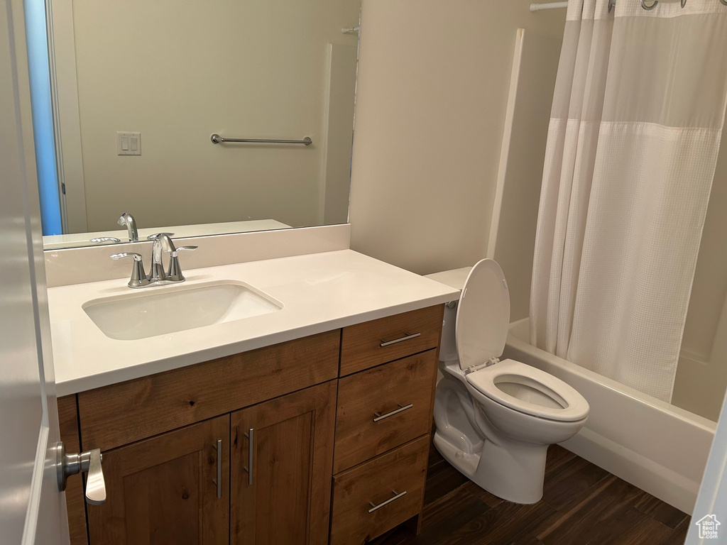 Full bathroom featuring vanity, toilet, shower / tub combo with curtain, and wood finished floors