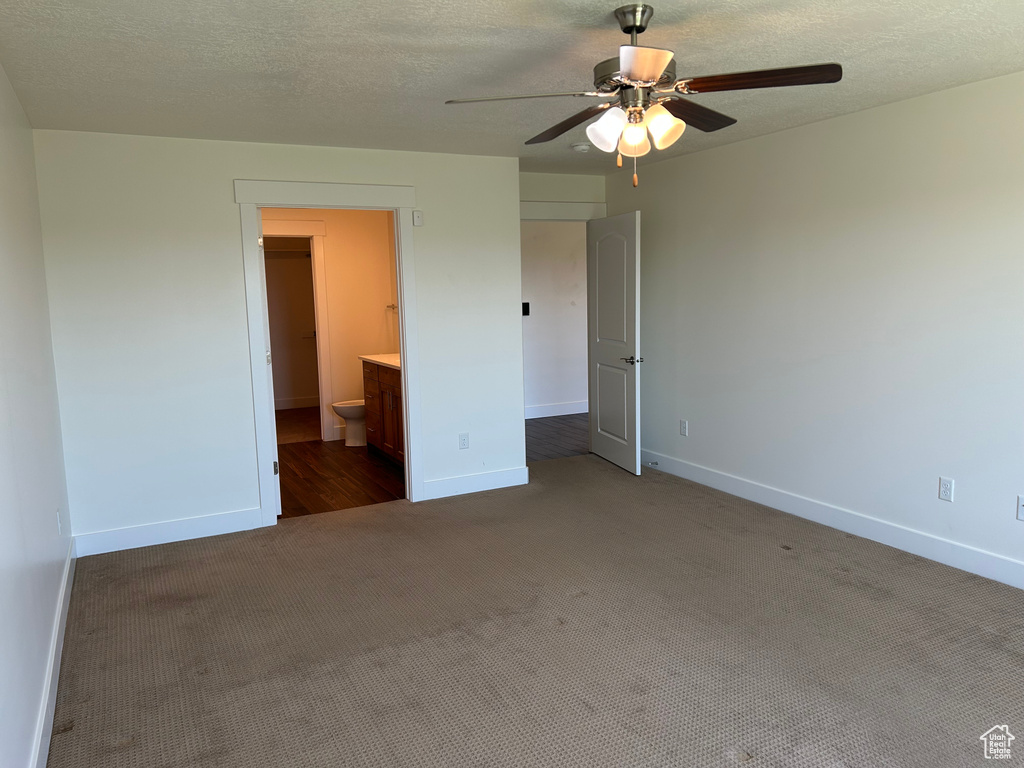 Unfurnished bedroom with carpet, baseboards, a textured ceiling, connected bathroom, and ceiling fan