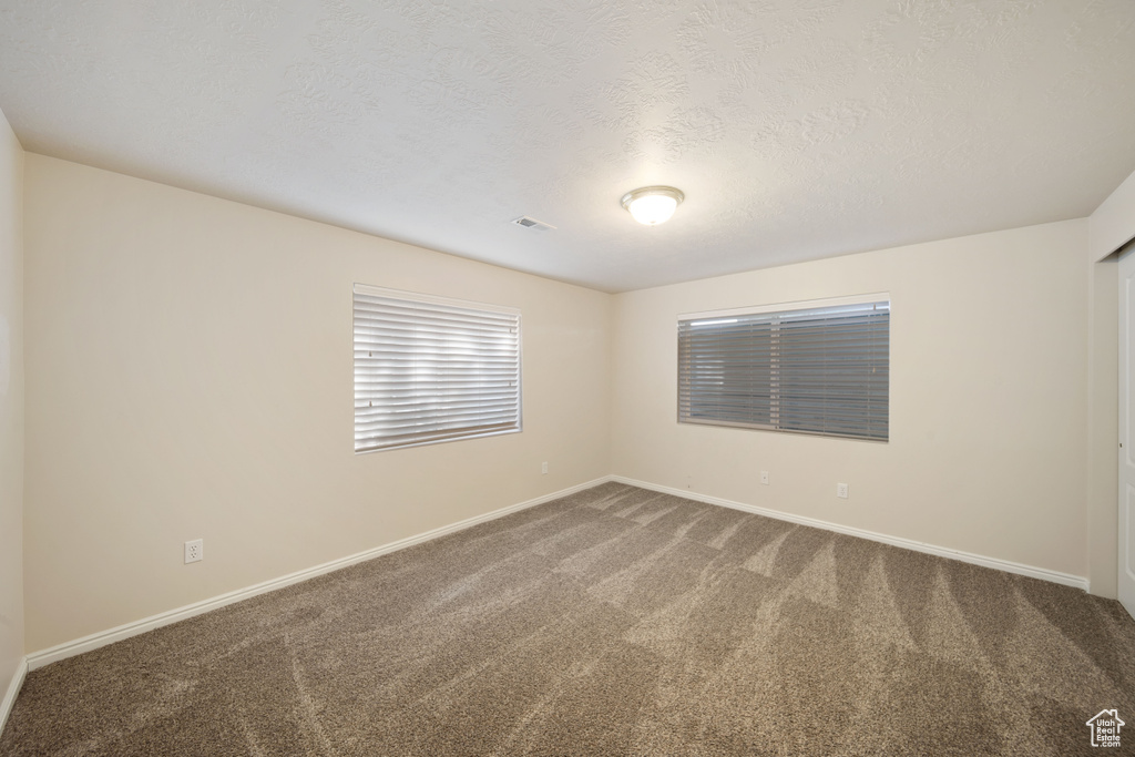 Spare room featuring carpet, baseboards, and a textured ceiling