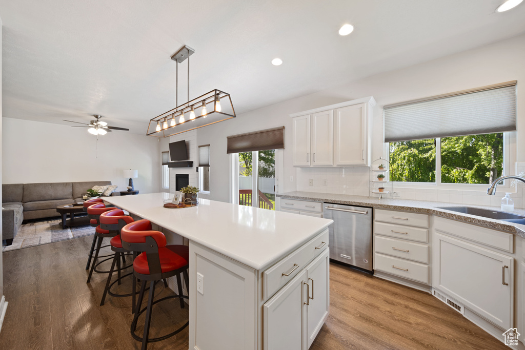 Kitchen with stainless steel dishwasher, a sink, open floor plan, a kitchen island, and a ceiling fan