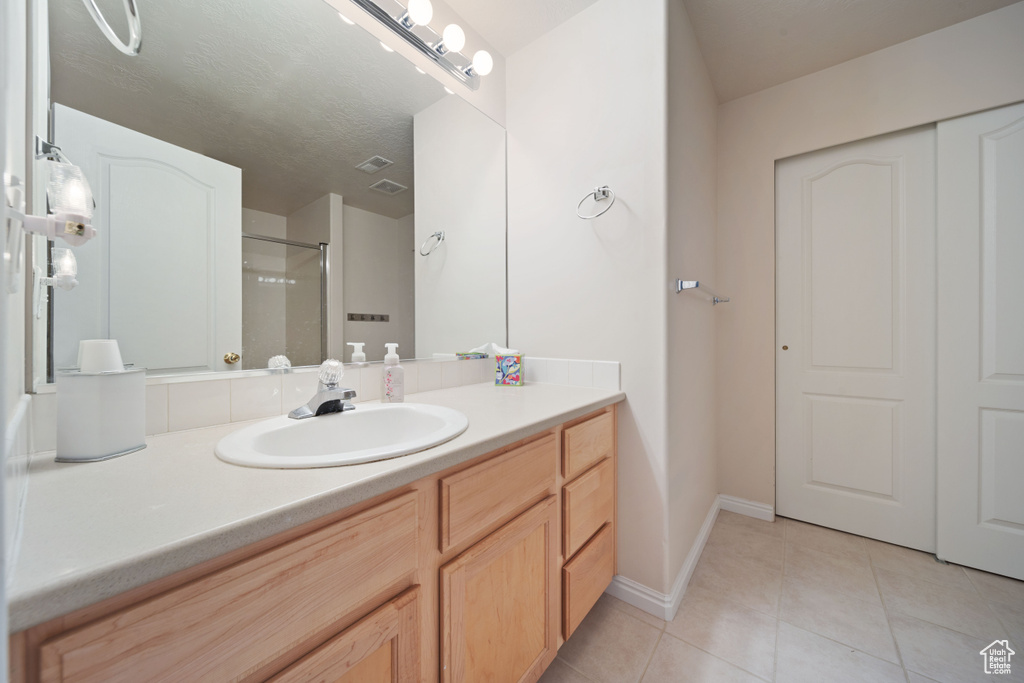 Full bath featuring vanity, tile patterned floors, a shower, and baseboards