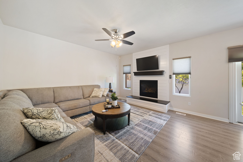 Living area featuring wood finished floors, ceiling fan, a fireplace, and baseboards