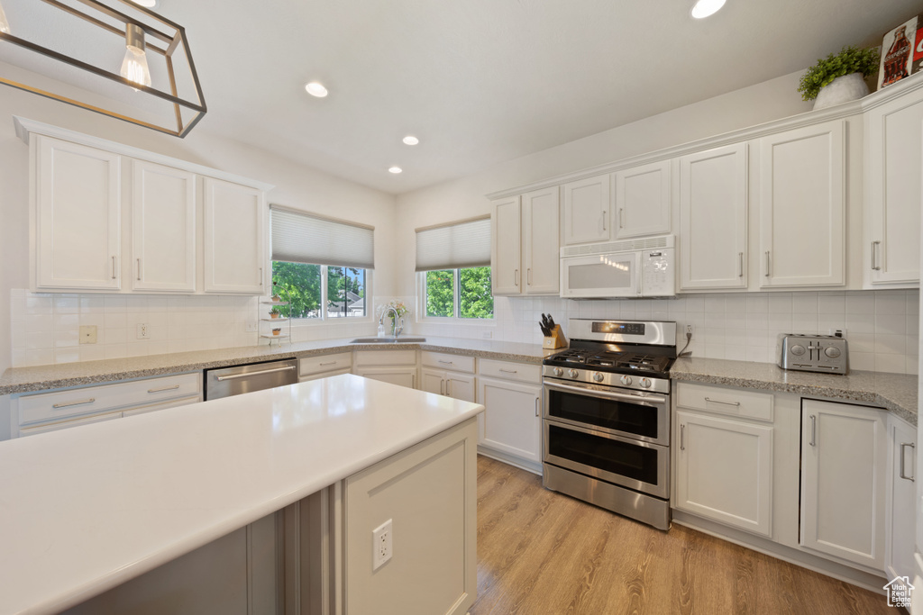 Kitchen featuring appliances with stainless steel finishes, recessed lighting, backsplash, white cabinets, and light wood-style flooring