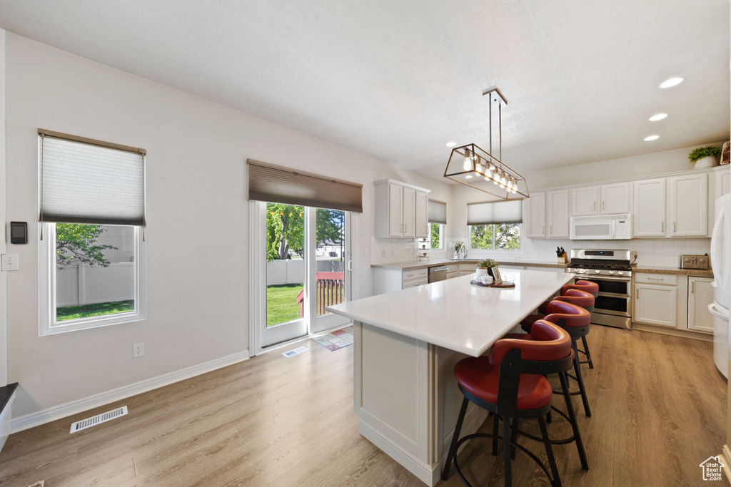 Kitchen featuring appliances with stainless steel finishes, light countertops, light wood-style flooring, a center island, and recessed lighting