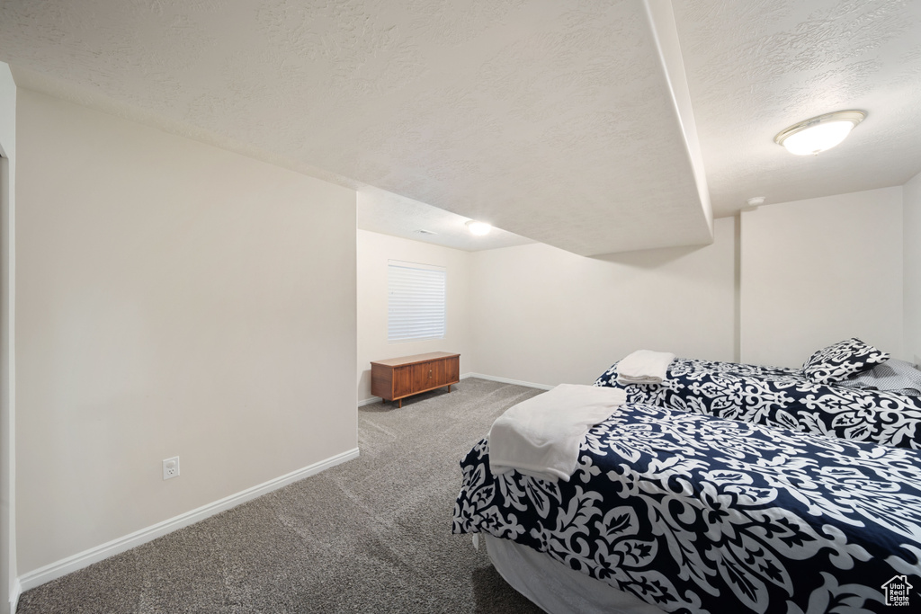 Bedroom with carpet flooring, a textured ceiling, and baseboards