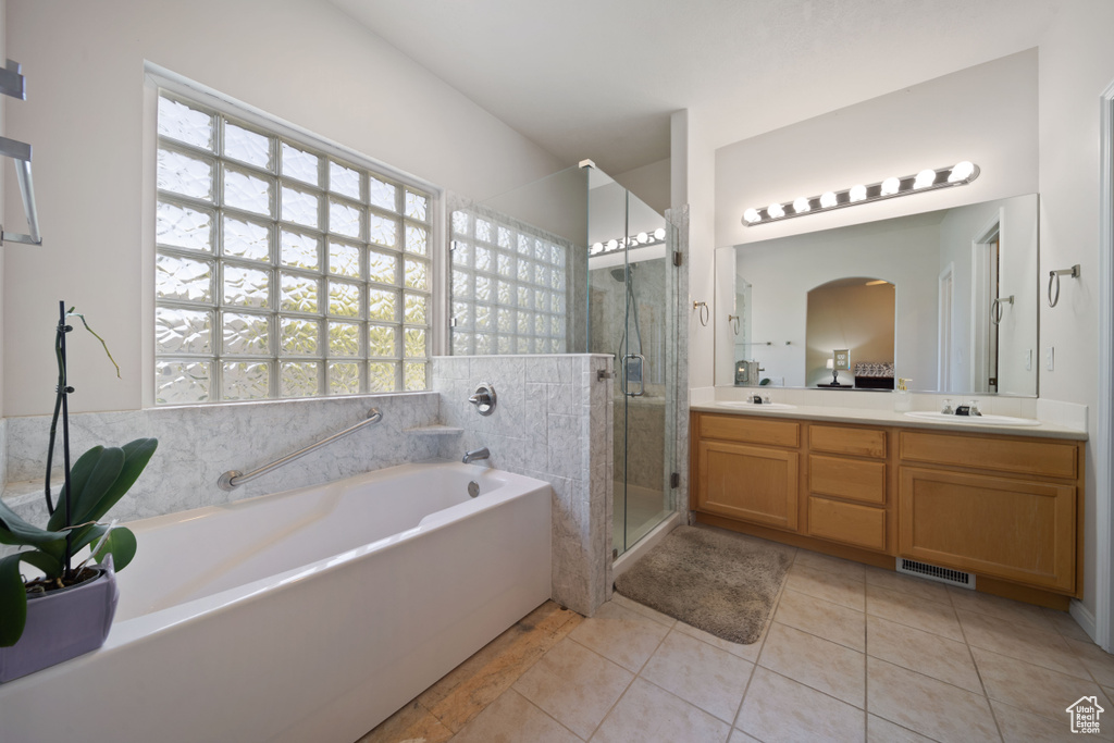 Bathroom featuring a garden tub, healthy amount of natural light, double vanity, and a stall shower